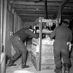 [Red Pedersen (left) and another man sorting fur pelts in a warehouse]. [between 1956-1960]