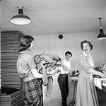 [Mrs. Delaute (right) washing and ironing Brownie uniforms with assistance from two guides, Iqaluit, Nunavut]. 1960