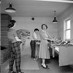 [Mrs. Delaute (right) washing and ironing Brownie uniforms with assistance from two guides, Iqaluit, Nunavut]. 1960