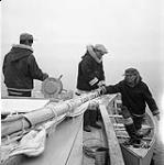 [Mike (left) boarding a boat with Captain Spyglassie's assistance as Isa watches, near Iqaluit, Nunavut]. 1960