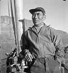 [Eetuk standing on boat, Leach Bay, Nunavut]. 1960