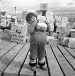 [Young girl [Shuvinai Mike] carrying a bag of sugar, Iqaluit, Nunavut]  1960