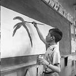 [Boy painting on paper attached to a blackboard, Iqaluit, Nunavut]. 1960