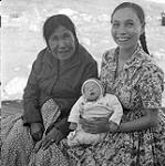 [Two women [Ooa, and Inga Alainga] sitting with a baby [Maleektoo] , Iqaluit, Nunavut]. 1960