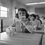 [Girl drinking cocoa and eating at school, Iqaluit, Nunavut]. 1960