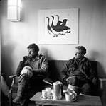 [Two fisheries researchers sitting on a couch at the Houston's residence, Kinngait, Nunavut]. 1960