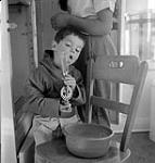 [Sam Houston licking a mixing utensil, Kinngait, Nunavut]. 1960