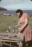 A First Nations woman [Lillian Rose Brown] canning salmon outdoors  [1947]