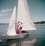 Donna Webb de Saskatoon et Jack Bruce de Prince Albert, préparent la voile pour passer une journée sur le lac Waskesiu, dans le parc national de Prince Albert, en Saskatchewan. juillet 1950