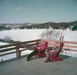 Skiers Suzanne Parent and Marc Cloutier on sun deck at Mount Kingston in Laurentians near Ste. Agathe, Québec. February 1953