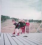 Deux garçonnets et deux fillettes jouent aux fers à cheval à Ste-Adèle  août 1954