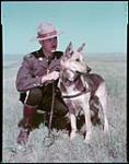 [RCMP const. B.A. Wright posing with police dog "Rough". Calgary, Alberta.]   août 1948.