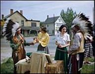 Betty Dixon (left) and Barbara Coutts select Indian souvenirs at St. David's, Ontario. At left is Chief Sky of the Six National Indian Reserve, Brantford, Ontario. At right is Warrior Running Deer.  1949.