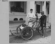 Le major H. W. Mulherin paie un conducteur de pousse-pousse devant l'Hôtel Royal à Phnom Penh, Cambodge. mai 1955