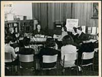 Une discussion ouverte de dix personnes présidée par R.T. Bell dans un bureau de la Bibliothèque publique de London en Ontario. mars 1945