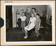 Famille canadienne typique debout dans la salle de séjour de leur maison. août 1944