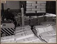 Employé de la Société Polymer de Sarnia transférant d'énormes piles de caoutchouc empaqueté sur des wagons de marchandise à côté de l'entrepôt de l'usine. mars 1946