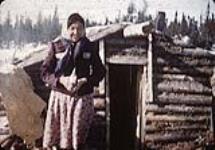 Young First Nation girl standing outside Chipewyan house, Duck Lake  n.d.