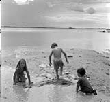 Enfants construisant un barrage avec du sable, Swan River, Manitoba  23 juin 1956.
