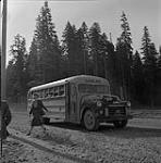 Femme s'éloignant d'un autobus scolaire, Kitimat, Colombie-Britannique. juin 1956.