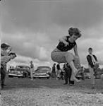 Woman executing a long jump, Swan River, Manitoba  June 30, 1956.