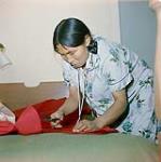 [Nepitia] cutting fabric for a parka, Cape Dorset, Nunavut  [between August 24-October 3, 1960].