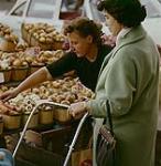 A shopper and a vendor looking over some of the produce in the Ottawa farmer's market. Ottawa, Ont.   1961
