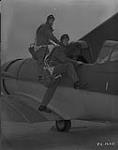 Pilots J.W. Hollway and H.G. Handley climb into their Harvard aircraft at No. 4 Service Flying Training School, Saskatoon, Saskatchewan  October 4, 1940