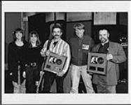 Aaron Tippin holding an album award - (left to right) Jill Snell (Manager, Artist Marketing), Shelley Snell (Assistant Manager, National Media Relations), Aaron Tippin, Ken Bain (Director, National Video/Country Radio Promo), Billy Craven (Manager for Aaron Tippin) [ca. 1992].