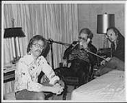 Elton John au téléphone, dans une chambre d'hôtel : (de gauche à droite) Scott Richards, Elton John . [entre 1973-1974].
