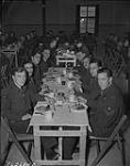 Station mess hall in England, F/S Pete Taylor, P/O Bill Newman, F/S Percy Moricn, Sergeant Roy Cottrell, F/L Jim Murray, messing committee president Sergeant Gordon Stewart, Sergeant Clare Gugins and Sergeant Alexander Reid. N.D.
