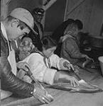 Inuit cleaning Arctic char. Aug. 1960