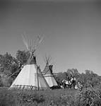 [Indigenous cadets sitting on a horse by two teepees]. [between 1900-1976]