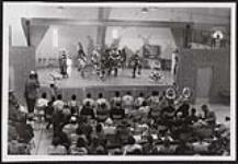 Chicken dancers on stage of community hall. 1959
