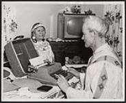 Senator James Gladstone at his typewriter as his wife looks on. [ca. 1958]