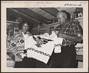 [Chief Ed Underwood and his wife, joint managers of the Goldstream Cooperative, which coordinates production and sales of Cowichan wool sweaters and other knit goods made by Coast Salish women, with some of their wares]. Original title: Chief Ed Underwood and his wife, joint managers of the Goldstream Cooperative, which coordinates production and sales of Cowichan wool sweaters and other knit goods made by Salish Indians, with some of their wares  1960