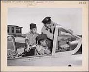 [Two young Cree boys from squadron 632 at Moose Factory, Ont. get aircraft instruction from F/L J. Rousille of Squadron 687 in Montreal]. Original title: At the summer camp at Clinton, Ont. two young Indians from Squadron 632 at Moose Factory, Ont. get aircraft instruction from F/L J. Rousille of Squadron 687 in Montreal. [between 1900-1976]