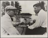 [Joseph Land, an Anishinaabe painter receives instruction from John Martin at the Quetico Conference and Training Centre]. Original title: Joseph Land, a young Indian painter from Whitedog Reserve, in northern Ontario, receives instruction from John Martin, well-known Ontario artist at the Quetico Conference and Training Centre. [ca. 1960]