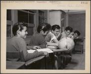 Boys of Grades 8 and 10 find that the globe helps them with their studies of geography. [between 1900-1976]