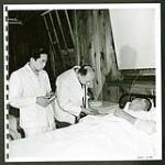 Staff doctor at the hospital at Tashme injects a hypo while an orderly looks on. [1945/06/16-1945/06/28]