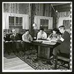 Mr. Maag, delegate of the International Red Cross, talks with Japanese committee at Tashme, B.C. Next to the Japanese stenographer an interpreter translates proceedings. Mr. Maag inquires into the social welfare of evacuees, and also receives complaints. [1945/06/16-1945/06/28]