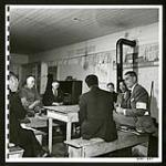 In the Buddhist church at Picture Butte, Alberta, Mr. Maag talks with Japanese delegates at a committee meeting. Through these committees the Commission transmits its wishes to evacuees. Japanese representatives are chosen by the evacuees by popular vote. [1945/06/16-1945/06/28]