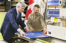 [Prime Minister Stephen Harper helps Rick Mostert, President of F.C. WoodWorks inc., manufacture an F.C. WoodWorks inc. product during his visit to the facility] 23 April 2015