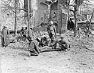 Porteur de civière et prisonnier allemand mettant des pansements sur un Canadien blessé lors de la prise d'Arleux (France) [ca 28-29 avril 1917].