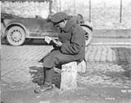 A Canadian soldier sitting on a milestone in Flanders. October, 1917 Oct., 1917.