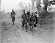 Tanks advancing.  Prisoners bring in wounded wearing gas masks.  Battle of Amiens août 1918.