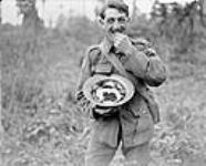 A Canadian enjoying blackberries which he had just gathered in Bourlon Wood. Advance East of Arras. October, 1918 Oct. 1918.