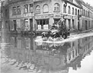 Civilians driving to their homes through flooded streets of Valenciennes on a Canadian car. November, 1918 Nov. 1918.