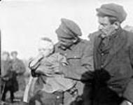 (Belgian) A Canadian pacifies a little Belgian baby near Mons, whose Mother was killed by an enemy shell; the child was wounded in its Mother's arms. The Father is seen in the picture. November, 1918 novembre 1918