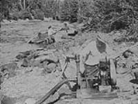 Olsen shovels gravel into launder, water for which is provided by small gas pump, Horsefly River, B.C 1938